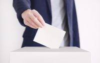 Mann som legger stemmeseddel i urnen
